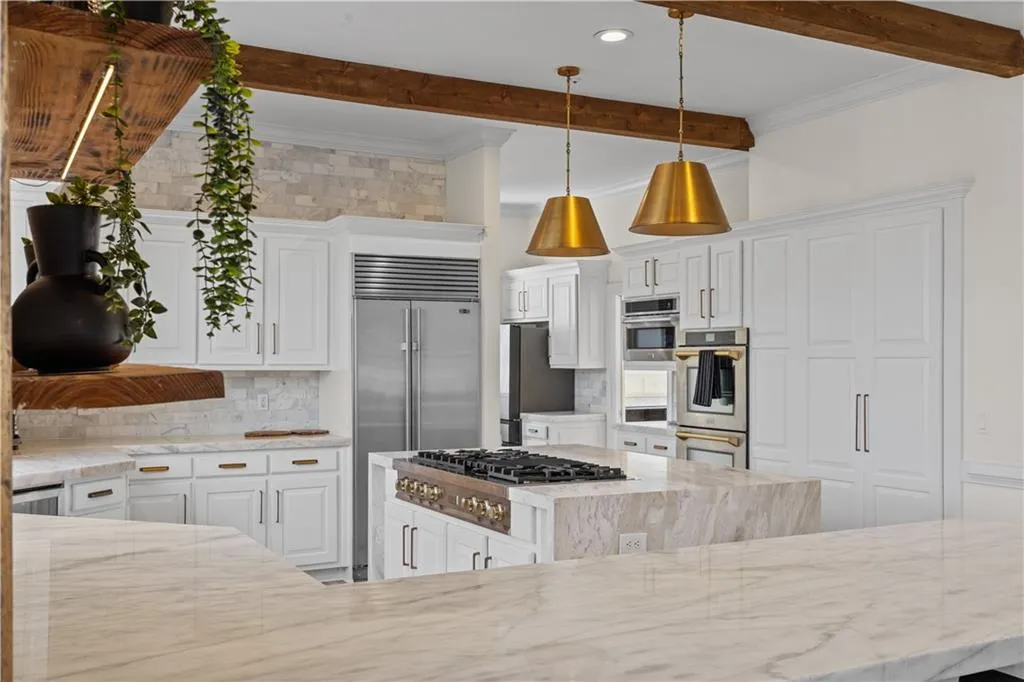 Kitchen with crown molding, light stone counters, stainless steel appliances, tasteful backsplash, and hanging light fixtures