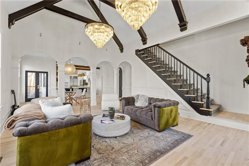 Living area with arched walkways, ornate columns, hanging lights, a decorative wall, and light wood finished floors