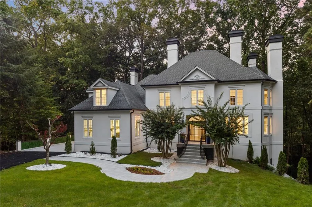 View of front facade featuring a front yard, a chimney, stucco siding, and a shingled roof