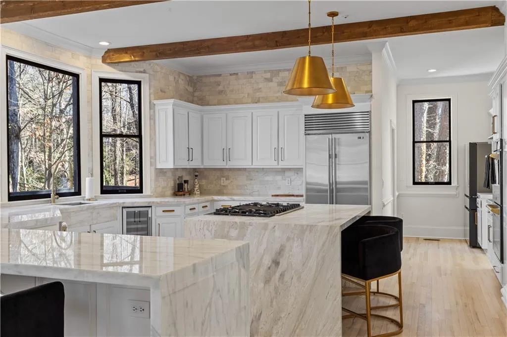 Kitchen with crown molding, a kitchen bar, light stone counters, white cabinets, and stainless steel appliances
