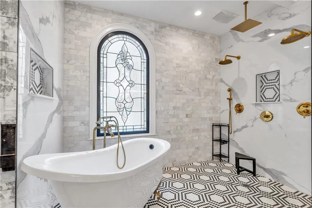 Full bath featuring tile walls, a freestanding tub, and a marble finish shower