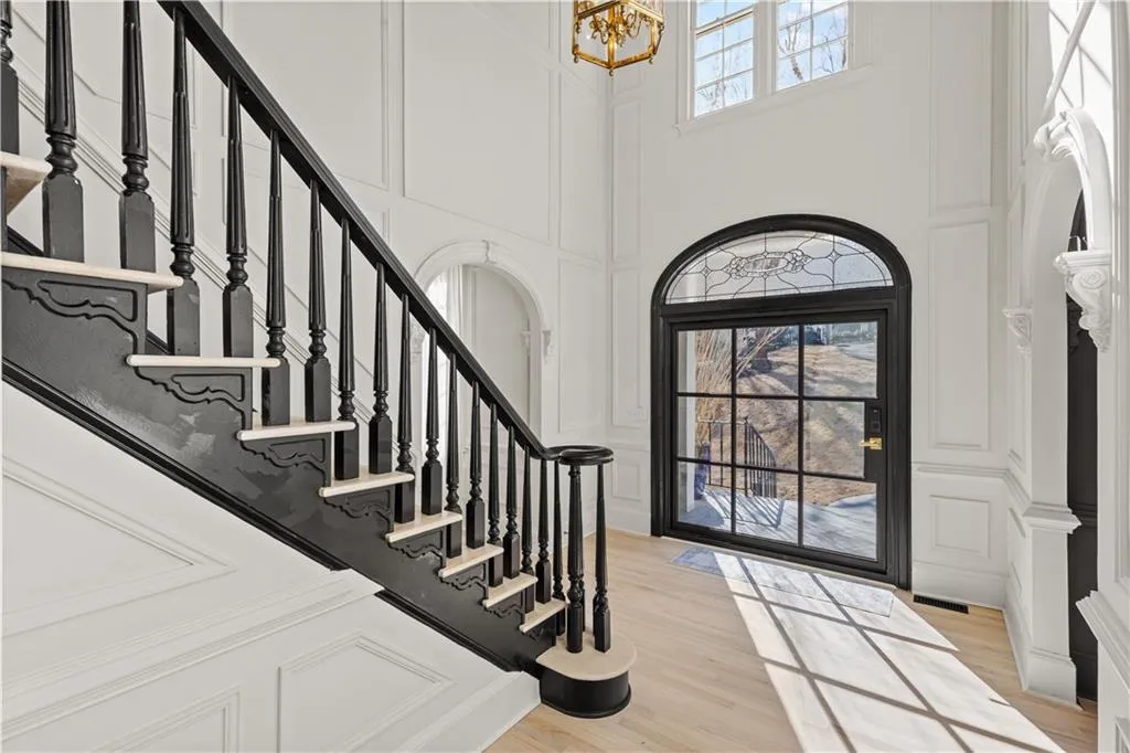 Entrance foyer featuring a decorative wall, plenty of natural light, light wood-style flooring, a high ceiling, and hanging lights