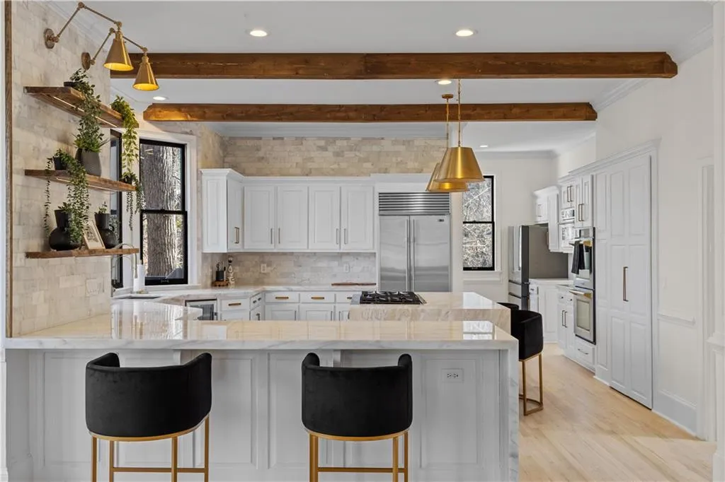 Kitchen with white cabinets, a peninsula, a kitchen breakfast bar, tasteful backsplash, and crown molding