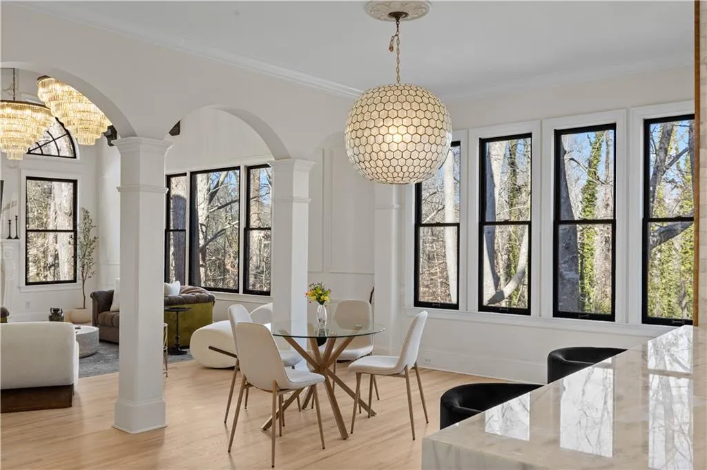 Dining area with suspended lighting, arched walkways, light wood-type flooring, and crown molding