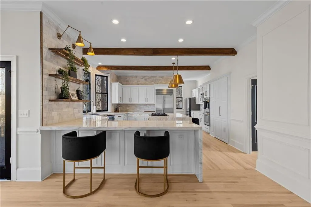 Kitchen with white cabinetry, a kitchen breakfast bar, light wood-style floors, a peninsula, and ornamental molding
