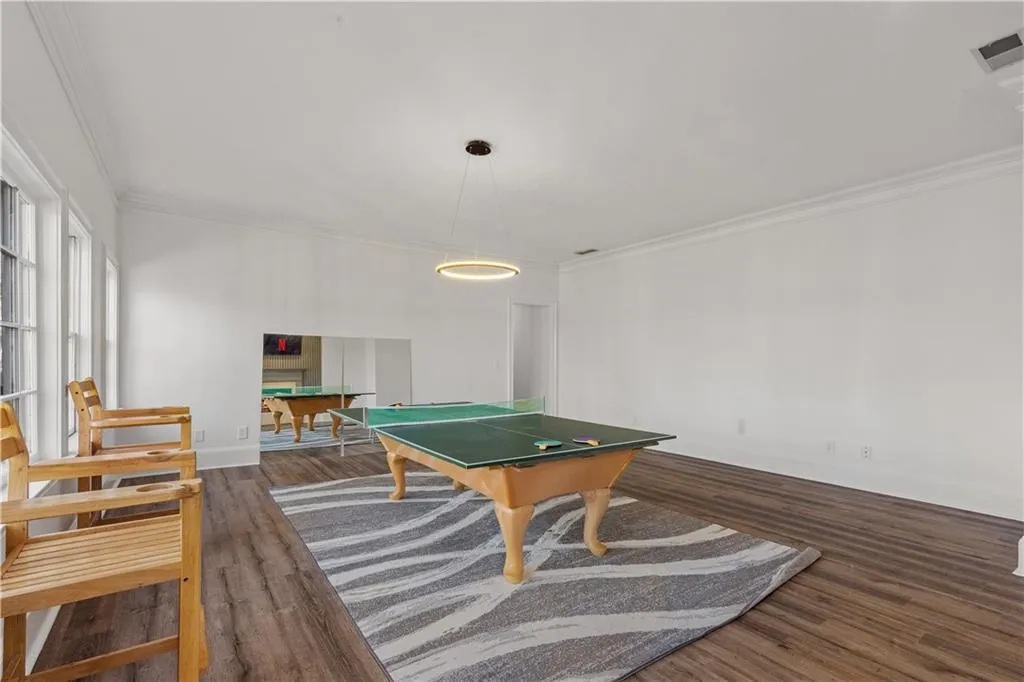 Recreation room with billiards table, ornamental molding, and dark wood-style floors