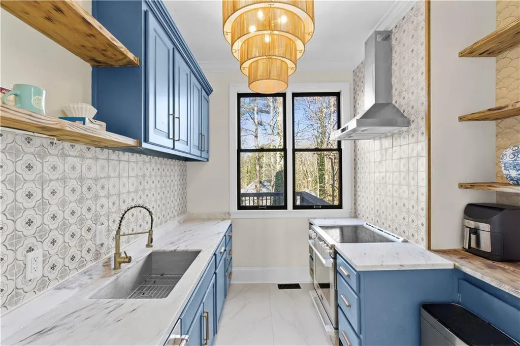 Kitchen with open shelves, blue cabinets, stainless steel electric stove, light stone counters, and tasteful backsplash