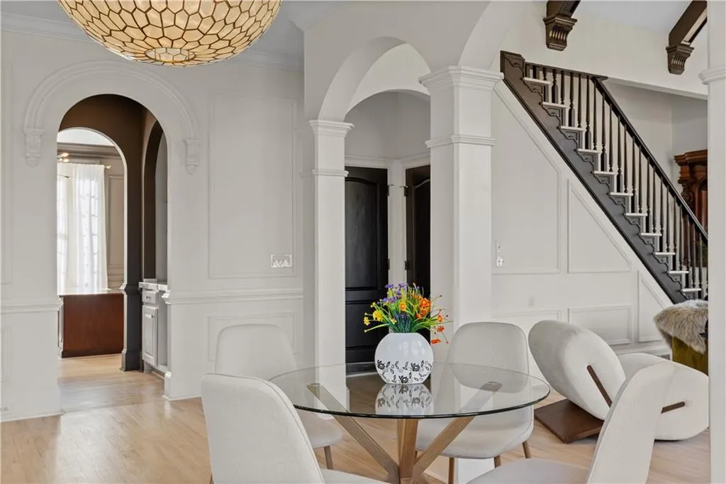 Dining space featuring light wood-type flooring, arched walkways, and crown molding