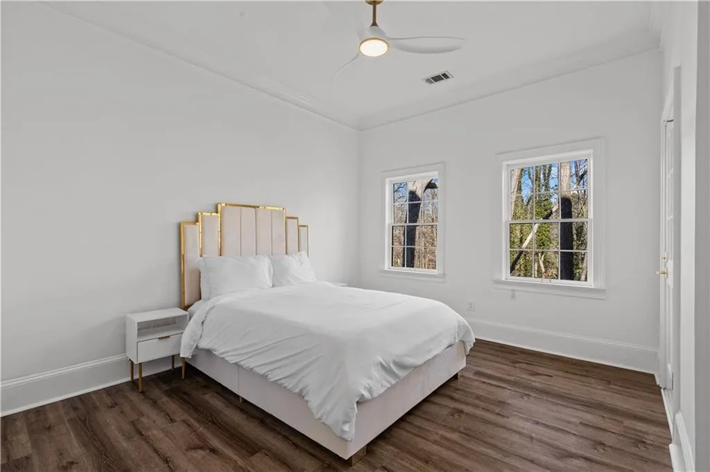 Bedroom with ornamental molding, dark wood-style floors, and ceiling fan