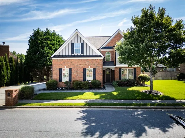 Brick veneer facade with white siding gables and black shutters