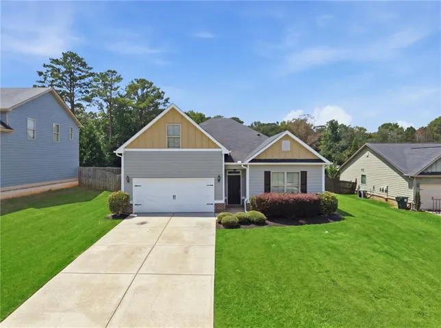 Single-story residence featuring light gray siding with a darker gray garage facade and yellow gable accents