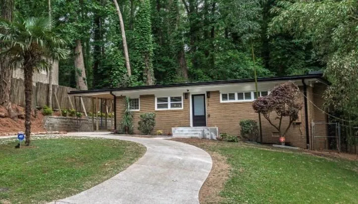 Brick exterior with a covered entryway, multiple windows, and a curved concrete driveway