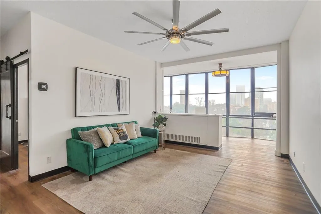 Living room with hardwood / wood-style flooring, a barn door, radiator, and ceiling fan