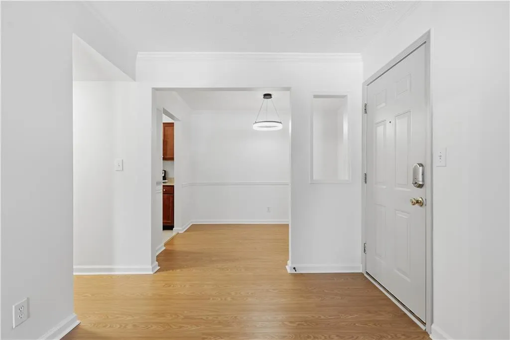 Hallway with light wood-type flooring and ornamental molding