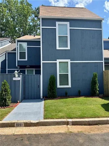 Two-story exterior featuring blue vertical siding with white trim, a brown shingle roof, and a private side entrance