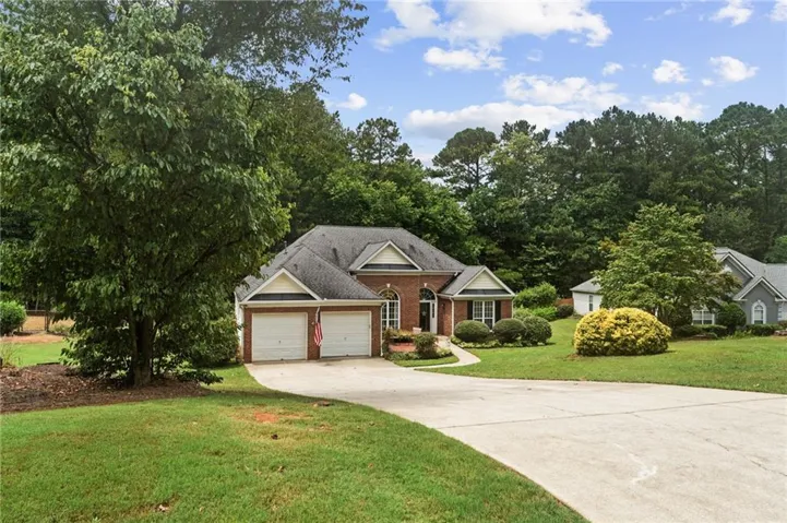 View of front facade featuring driveway, brick siding, a front lawn, and a garage