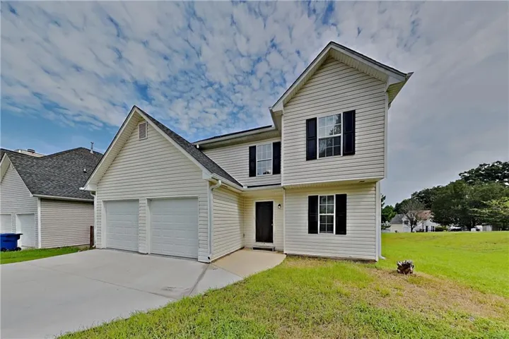 Two-story exterior with light-colored siding, black shutters, and a two-car garage