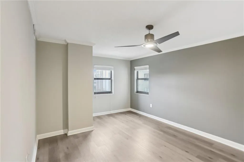 Empty room with crown molding, hardwood / wood-style floors, and ceiling fan