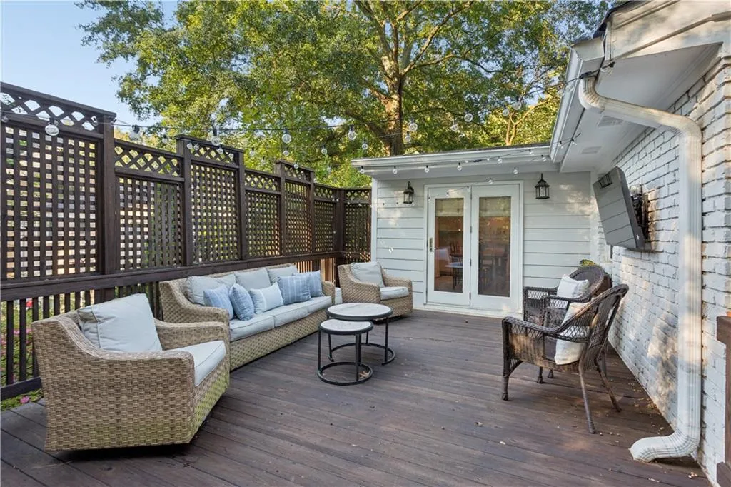 Expansive wood-plank deck featuring white brick exterior siding, custom wood lattice privacy screening, and glass-paned double doors