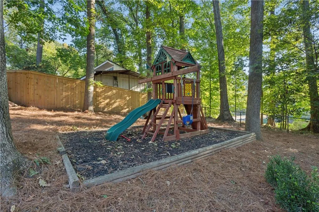 Wooded backyard featuring a fenced perimeter, mulch-surfaced recreation area, and mature trees