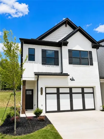 White exterior with black trim, black paneled garage door, and dark wood-finish support beam