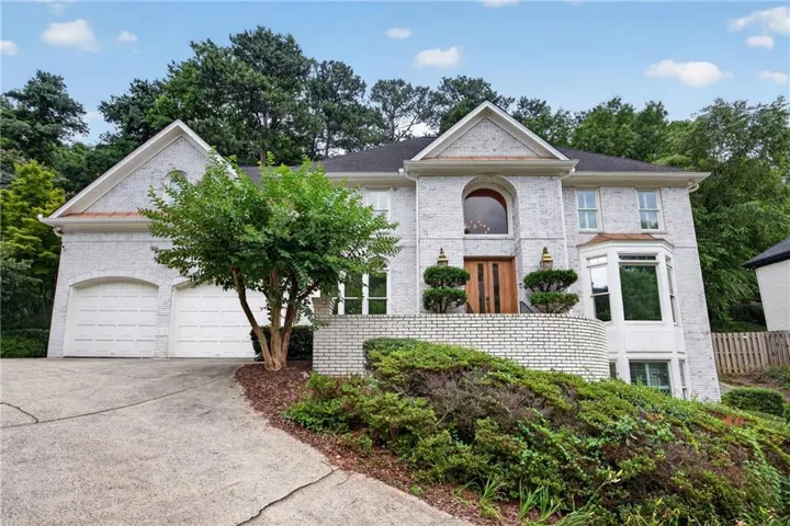 Stately brick exterior featuring a prominent arched window, a two-car garage, and a bay window on the lower level