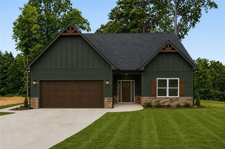Exterior featuring dark green siding, stone accents, a dark shingle roof, wood-look garage door, and a covered entry