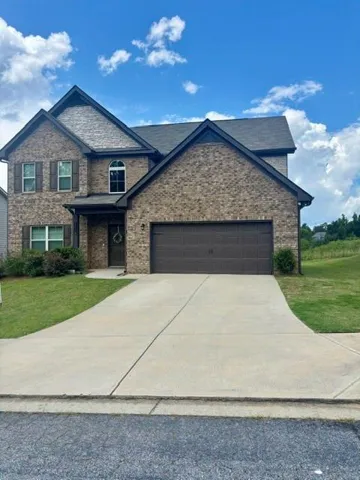 Brick exterior with stone accents, covered front entry, 2 car attached garage, and concrete driveway.