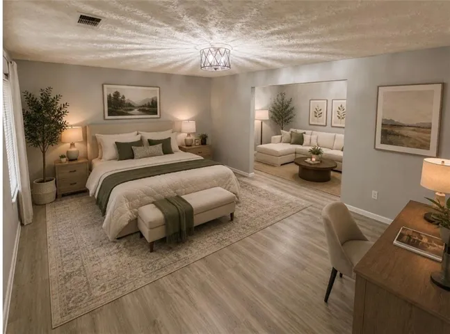 Expansive living area with wood-finish flooring, featuring a dedicated bedroom space and an open-concept sitting area