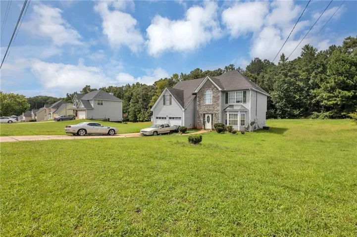 Two-story residence with a stone and siding facade, an attached garage, and a bay window