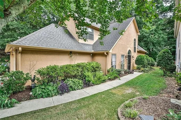 Stucco exterior with an arched entry, prominent dormer, and a concrete walkway