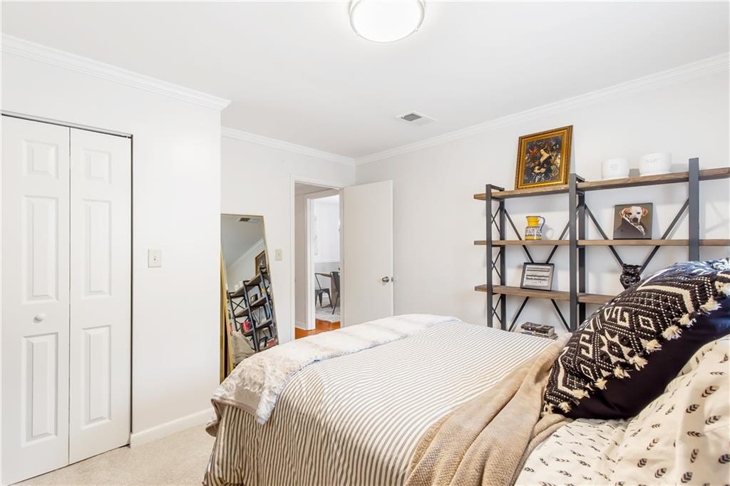 Carpeted bedroom with a closet and crown molding
