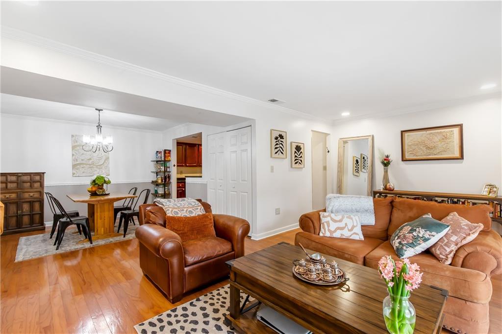 Living room with a chandelier, light hardwood / wood-style flooring, and crown molding