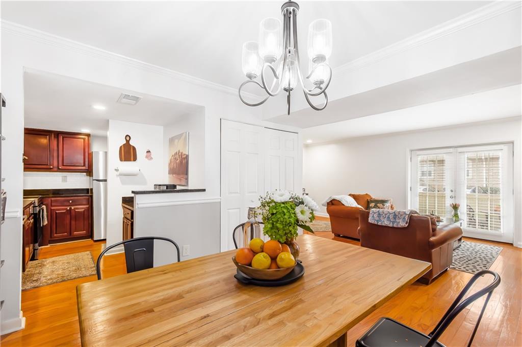 Dining area with light hardwood / wood-style flooring, crown molding, and a notable chandelier
