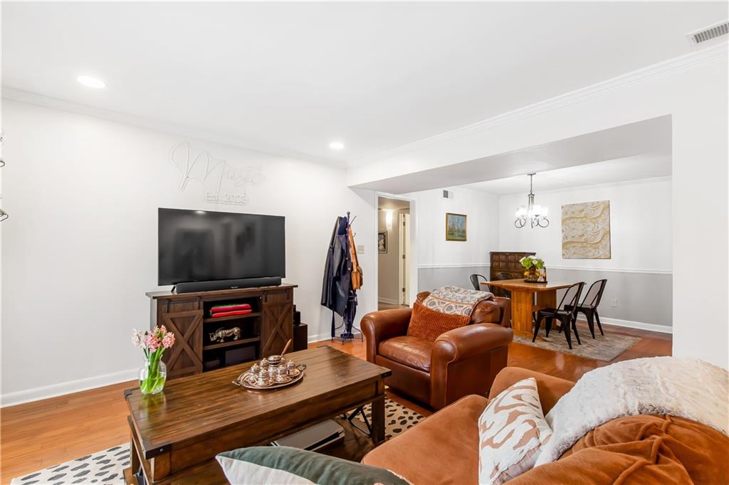 Living room featuring an inviting chandelier, light hardwood / wood-style flooring, and ornamental molding