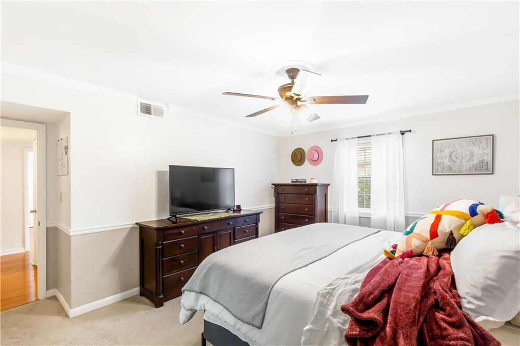 Bedroom featuring light carpet, ceiling fan, and ornamental molding
