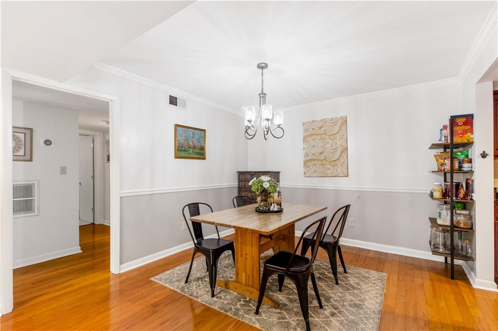 Dining area featuring light wood-type flooring, an inviting chandelier, and crown molding