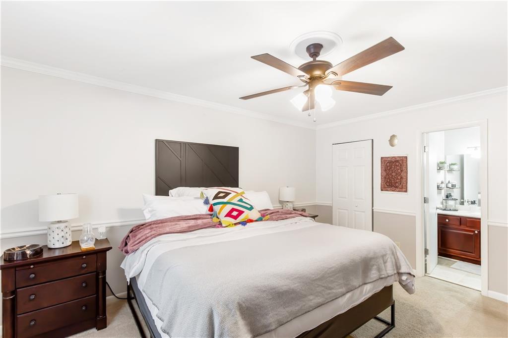 Bedroom featuring light carpet, connected bathroom, ceiling fan, and ornamental molding