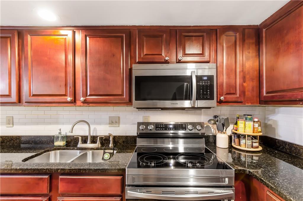 Kitchen featuring tasteful backsplash, sink, appliances with stainless steel finishes, and dark stone countertops