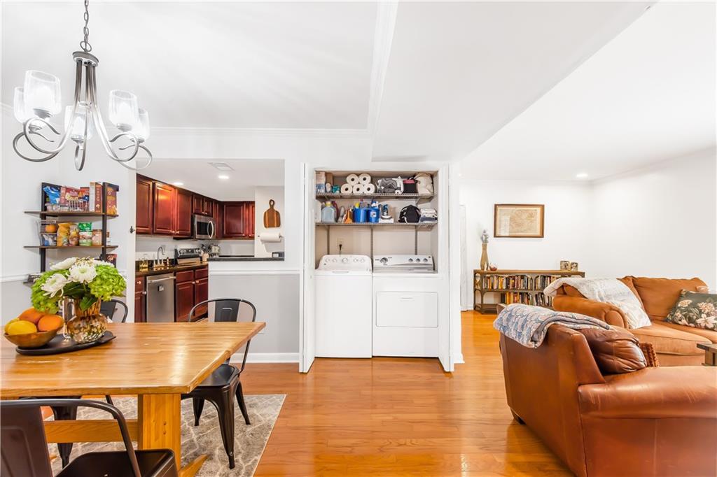 Kitchen with pendant lighting, stainless steel appliances, washer and dryer, a chandelier, and light hardwood / wood-style flooring