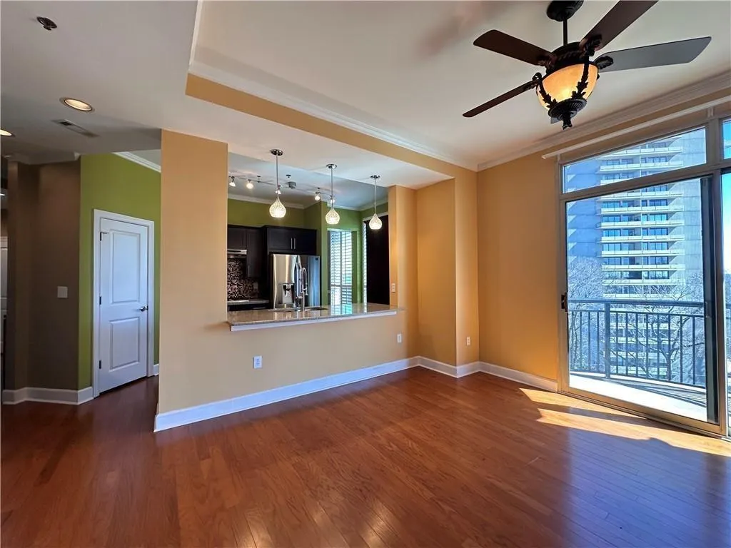 Unfurnished living room with crown molding, dark wood-style floors, and ceiling fan