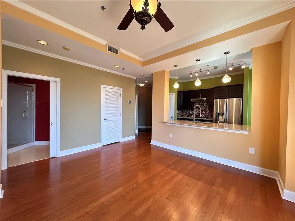 Unfurnished living room featuring dark wood-style floors, crown molding, and ceiling fan