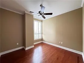Empty room with ornamental molding, dark wood finished floors, and a ceiling fan