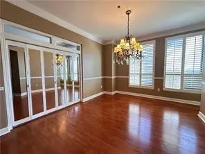 Unfurnished dining area with dark wood-type flooring, hanging lights, and ornamental molding