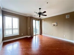 Spare room featuring dark wood-style flooring, ornamental molding, and a ceiling fan