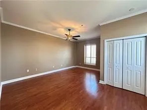 bedroom featuring crown molding, dark wood-type flooring, a closet, and ceiling fan