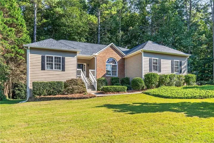 Charming brick and vinyl-sided ranch home set on expansive manicured grounds with mature tree backdrop