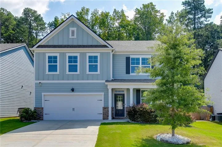 Two-story residence featuring light blue siding, a covered entry, an attached two-car garage, and a gable roof