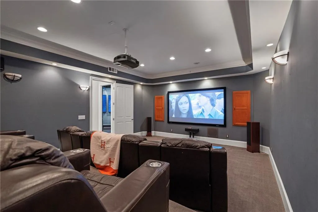 Carpeted home theater with ornamental molding, recessed lighting, and a tray ceiling
