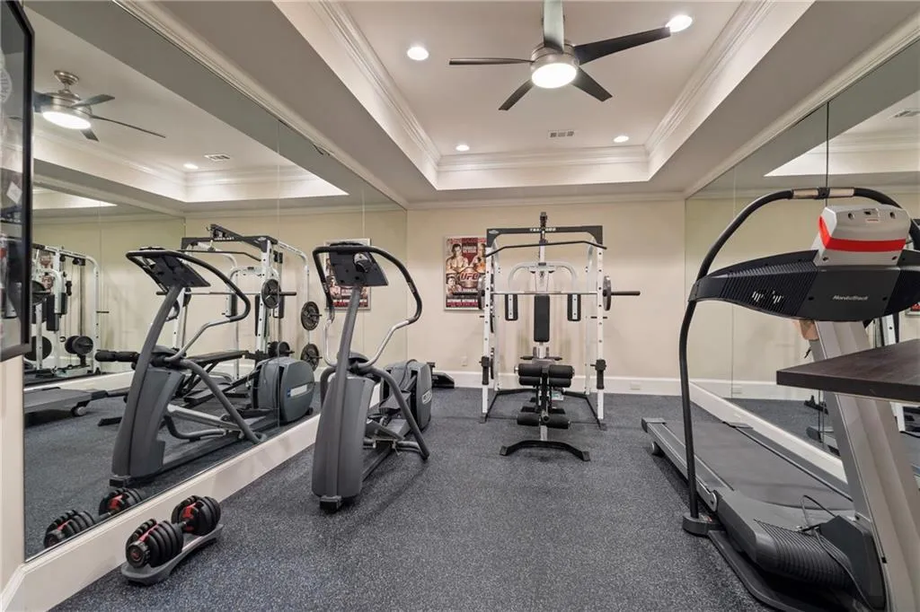 Workout area featuring ceiling fan, a tray ceiling, recessed lighting, and ornamental molding